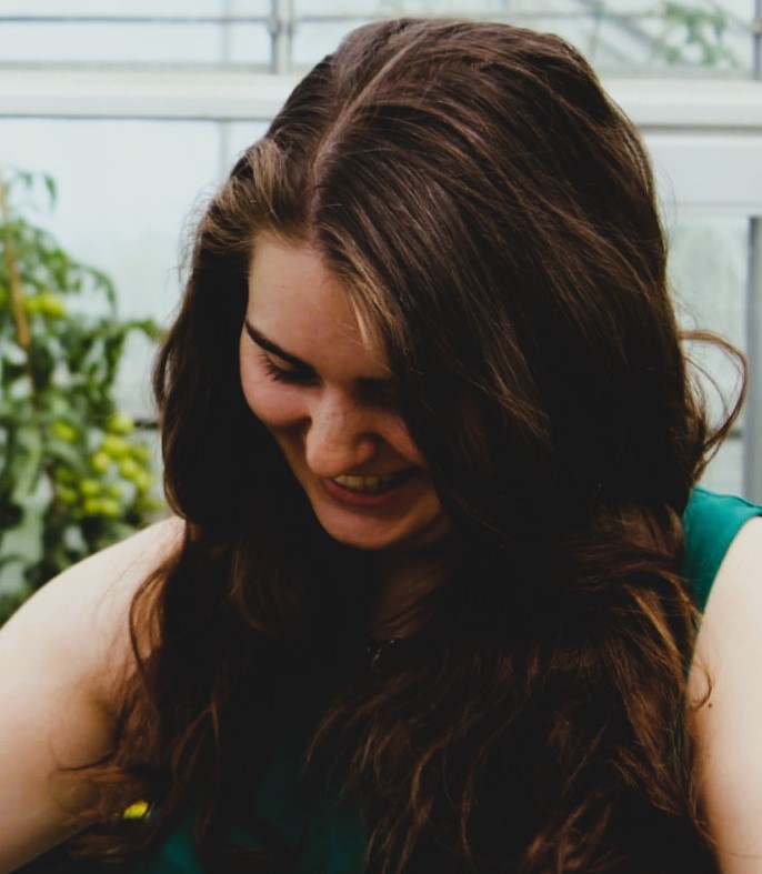 A white woman with long brown hair is looking down so her face is in shadows
